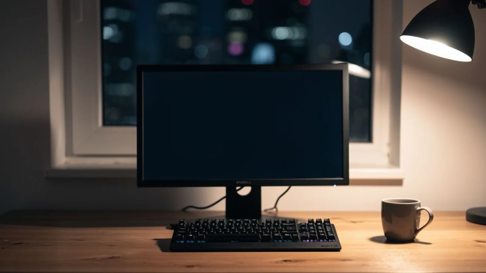A single workstation monitor on a wooden desk in a quiet home office at night, the screen dark, a desk lamp casting amber light across a keyboard — the builder's desk where the open-weights reply to Dario Amodei's essay was written. Illustration: DeAI
